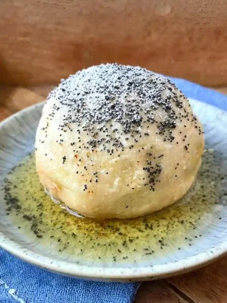 Germknödel mit Pflaumenmus – klassischer Germknödel mit Butter, Mohn und Puderzucker auf Teller