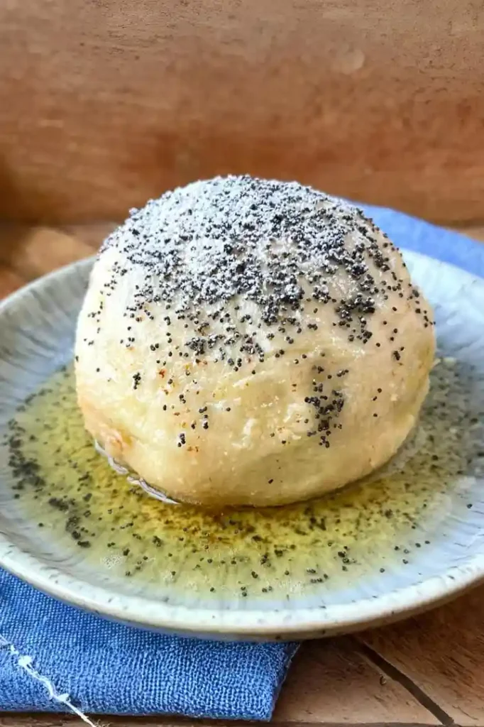 Germknödel mit Pflaumenmus – klassischer Germknödel mit Butter, Mohn und Puderzucker auf Teller