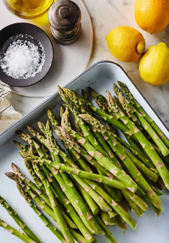 Grüner Spargel vorbereiten zum Grillen mit Marinade – frischer Spargel mit Öl, Zitrone und Gewürzen