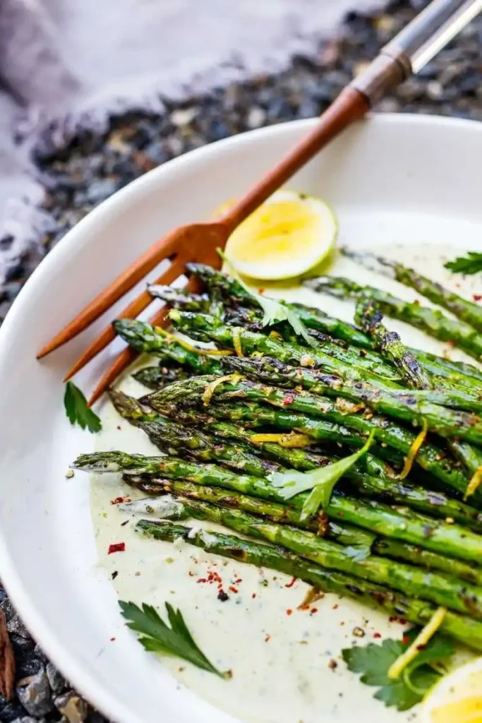 Gegrillter grüner Spargel mit Marinade und Zitrone – Spargel vom Grill auf Teller angerichtet