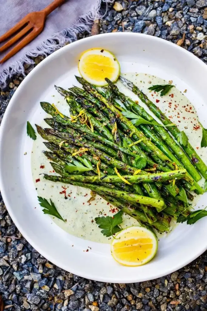 Gegrillter grüner Spargel mit Marinade und Zitrone – Spargel vom Grill angerichtet auf Teller