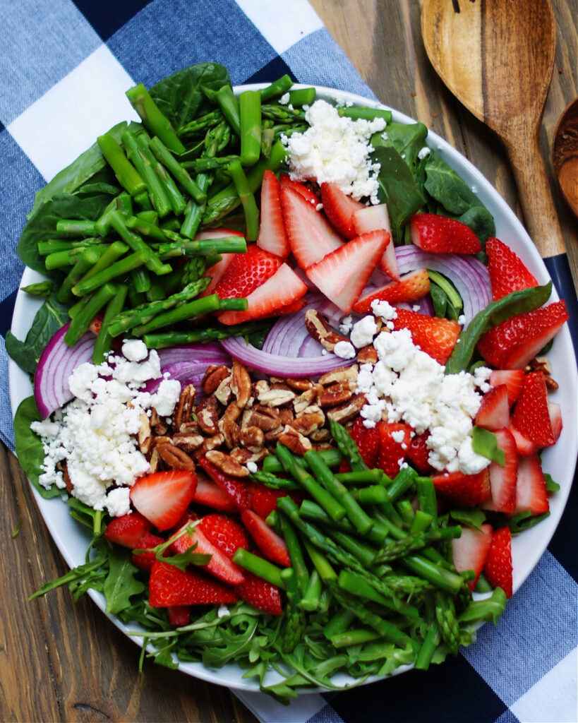 Grüner spargelsalat mit erdbeeren und feta vor dem Vermengen mit Spargel, Erdbeeren, Zwiebeln und Nüssen