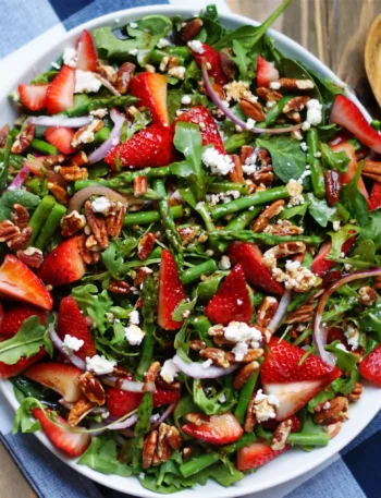 Grüner Spargelsalat mit Erdbeeren und Balsamico mit Feta, Nüssen und Rucola frisch serviert