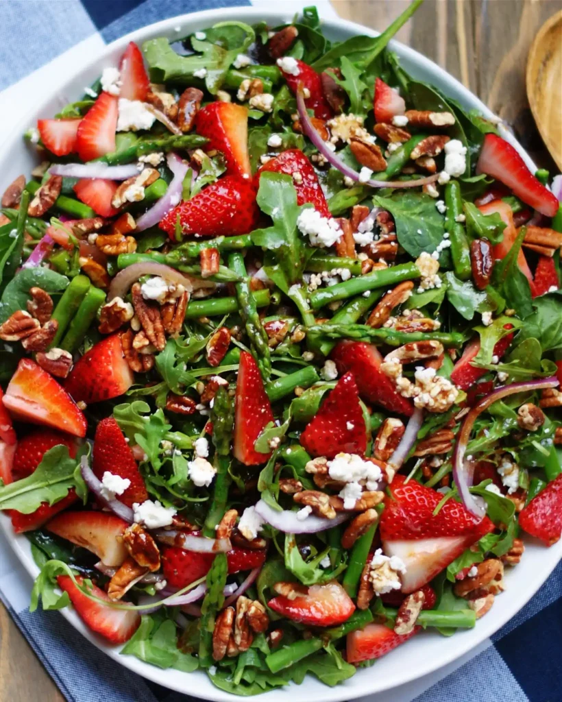 Grüner Spargelsalat mit Erdbeeren und Balsamico mit Feta, Nüssen und Rucola frisch serviert