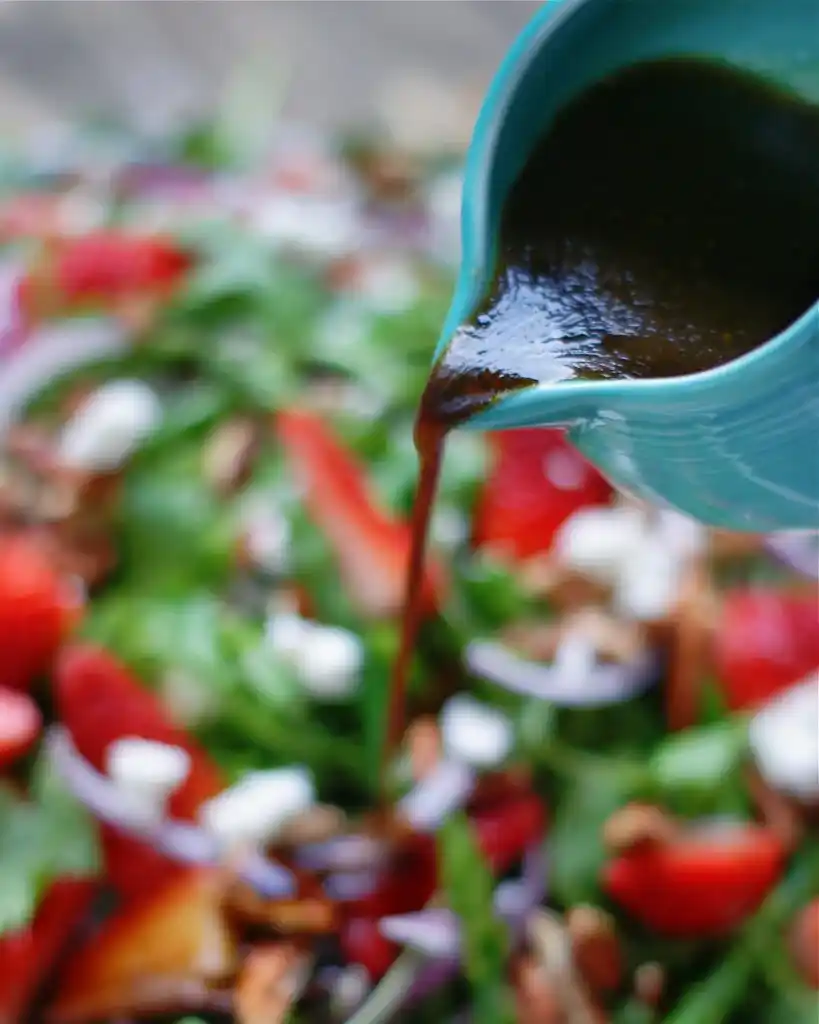 Balsamico Dressing wird über grüner spargelsalat mit erdbeeren und feta gegossen