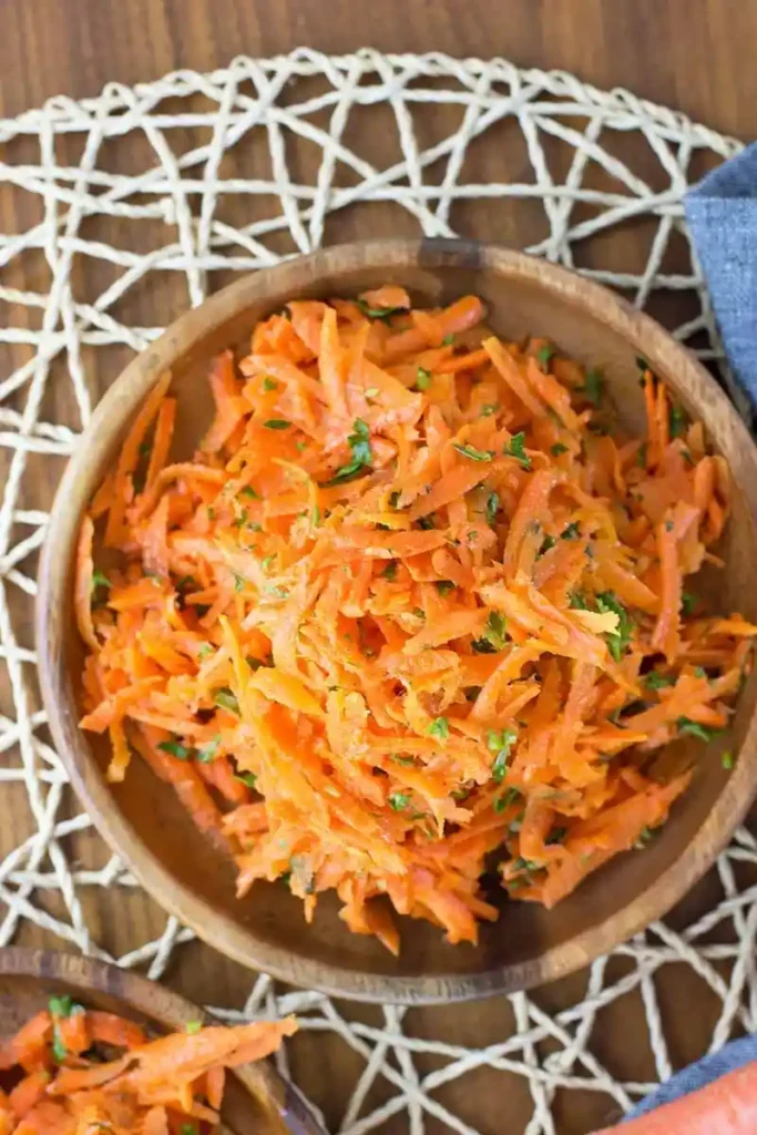 Karottensalat mit Apfel und klassischem Karottensalat Dressing nach Omas Rezept in einer Schüssel – frischer roher Karottensalat mit Kräutern