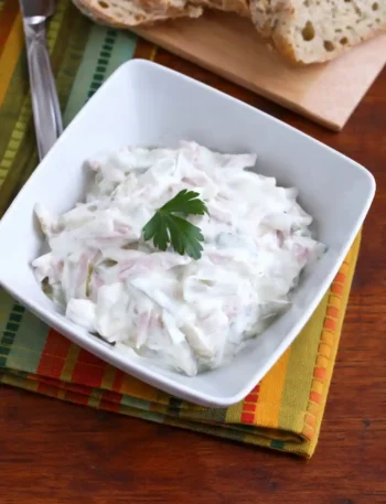 Omas fleischsalat rezept mit mayonnaise in einer Schüssel serviert mit Brot im Hintergrund
