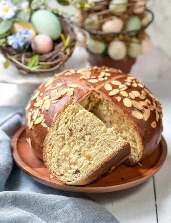 Saftiges Osterbrot Rezept mit Trockenhefe – Omas Osterbrot wie vom Bäcker mit Mandelblättchen angeschnitten auf Holzbrett