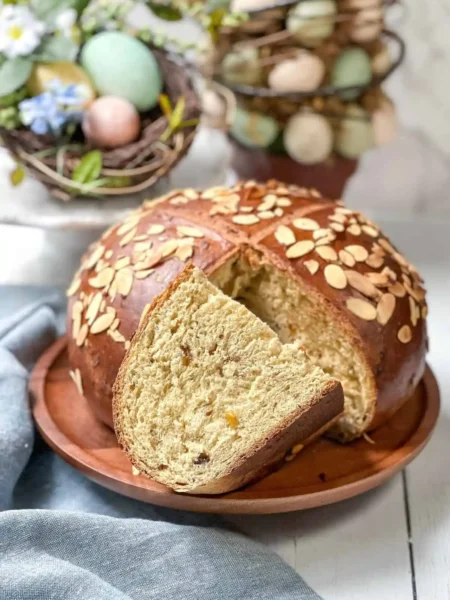 Saftiges Osterbrot Rezept mit Trockenhefe – Omas Osterbrot wie vom Bäcker mit Mandelblättchen angeschnitten auf Holzbrett