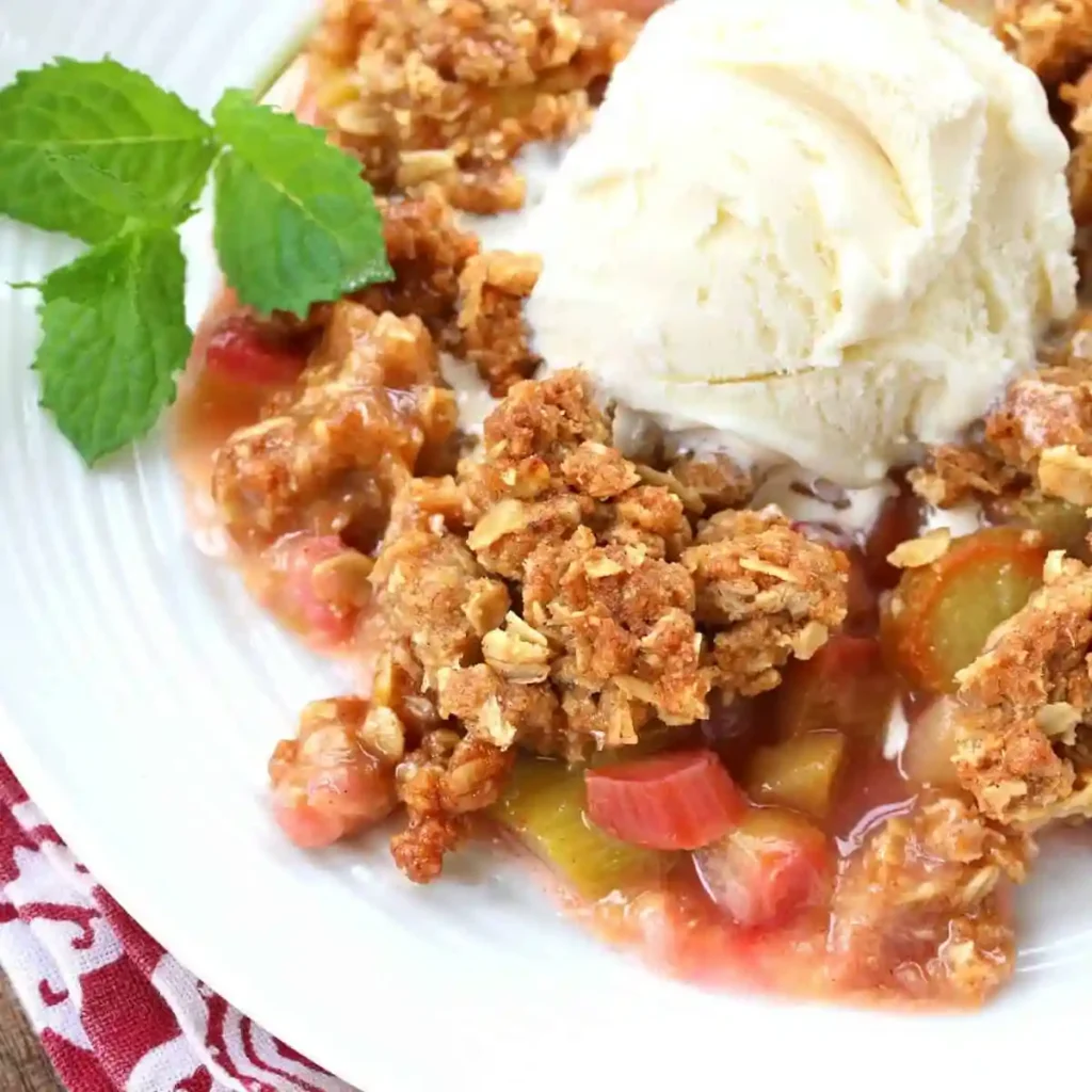 Rhabarber Crumble mit Haferflocken und Vanilleeis auf einem Teller – saftiger Crumble mit Rhabarber nach klassischem Rhabarber Crumble Rezept wie bei Oma.