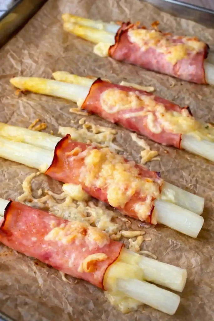 Spargel überbacken mit Schinken und Käse im Ofen – fertige Spargel Schinkenröllchen auf Backblech