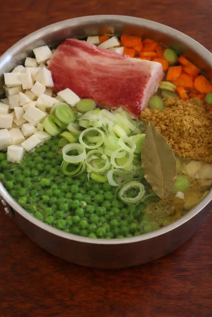 Erbsensuppe Rezept wie Oma im Topf mit Erbsen, Kartoffeln, Gemüse und Fleisch vor dem Kochen
