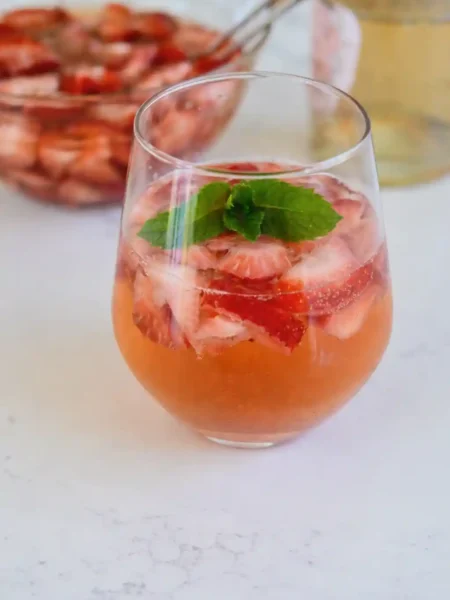 Erdbeerbowle klassisch mit Sekt und Weißwein im Glas, fruchtige Erdbeerbowle mit frischen Erdbeeren und Minze