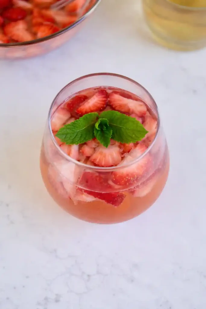 Erdbeerbowle mit Sekt und Weißwein im Glas, fruchtige Erdbeerbowle mit frischen Erdbeeren und Minze