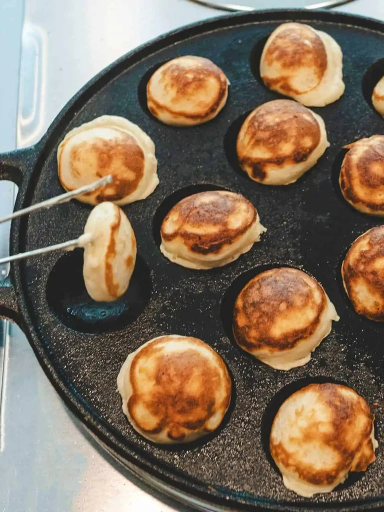 Holländische Poffertjes in der Poffertjes-Pfanne wenden für ein goldbraunes original Poffertjes Rezept