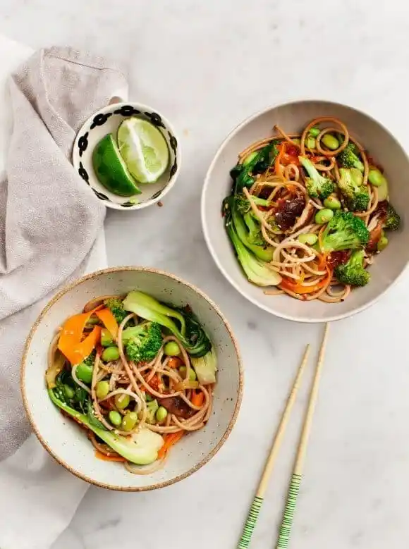 Pak Choi Pfanne mit Gemüse und Nudeln auf zwei Schüsseln serviert, asiatisches Rezept mit Brokkoli, Karotten und Edamame