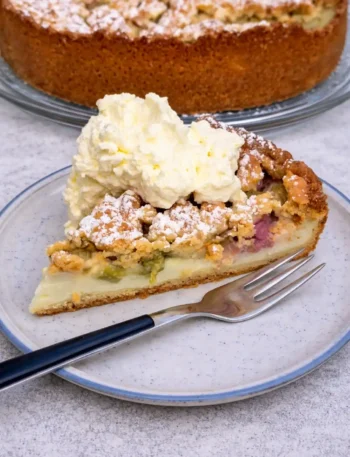 Rhabarberkuchen mit Pudding und Streusel in Springform mit Sahne serviert – saftiger Rhabarberkuchen nach Omas Rezept