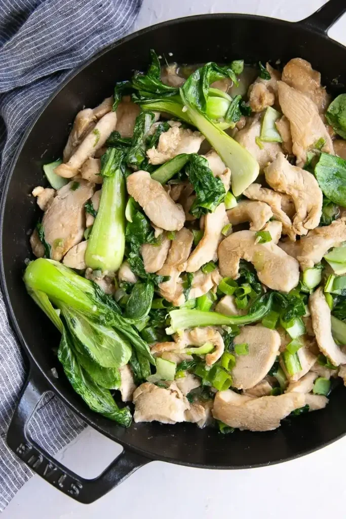 Pak Choi mit Hähnchen in der Pfanne – fertig gegarte Hähnchenbrust mit grünem Pak Choi und Frühlingszwiebeln