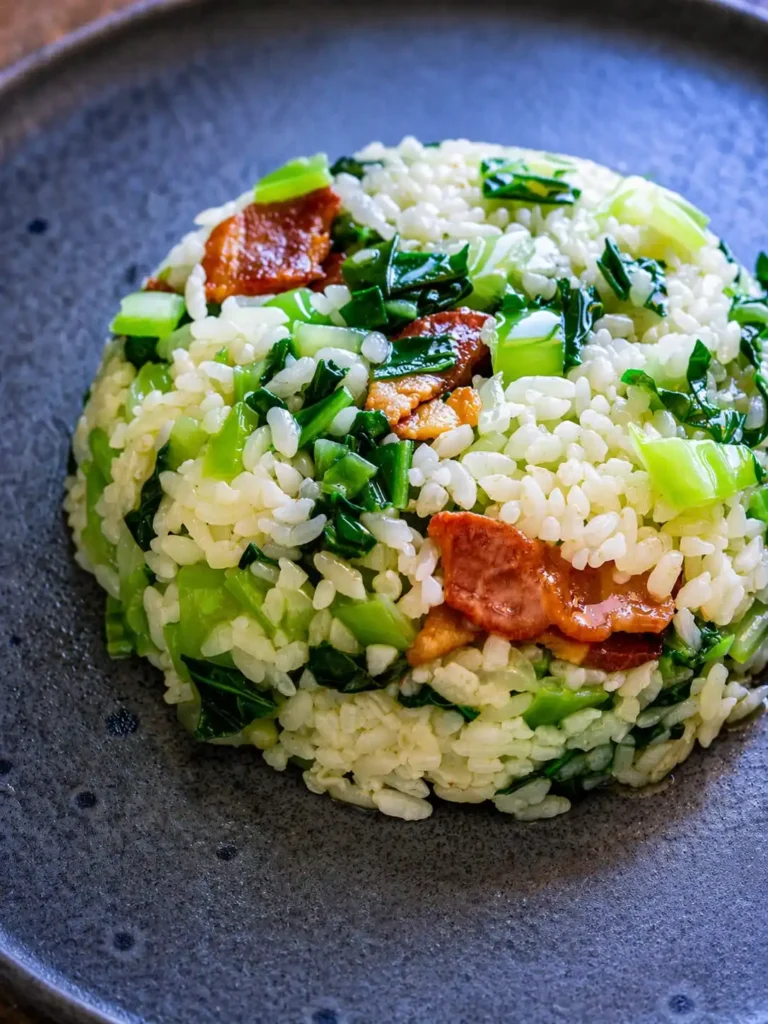 Pak Choi mit Reis aus der Pfanne mit Speck – gebratener Reis mit Pak Choi und knusprigem Bacon angerichtet auf einem Teller