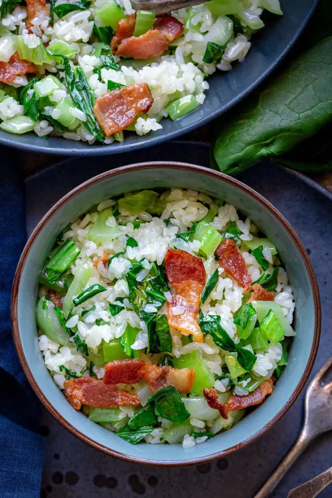 Pak Choi mit Reis aus der Pfanne mit Speck – gebratener Reis mit Pak Choi und knusprigem Bacon in einer Schüssel