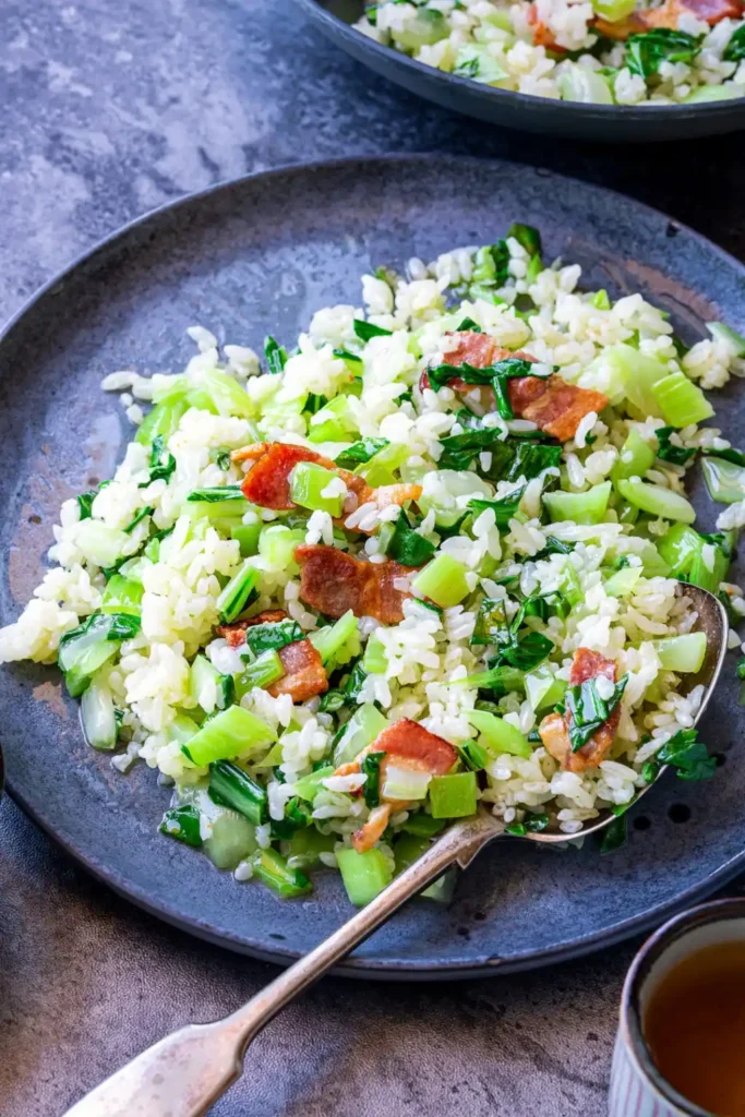Pak Choi mit Reis und Speck – gebratener Reis mit Pak Choi aus der Pfanne auf einem Teller serviert