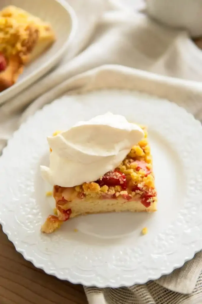 Rhabarberkuchen mit Hefeteig und Streusel mit Sahne – saftiger Hefekuchen mit Rhabarber Stück auf Teller