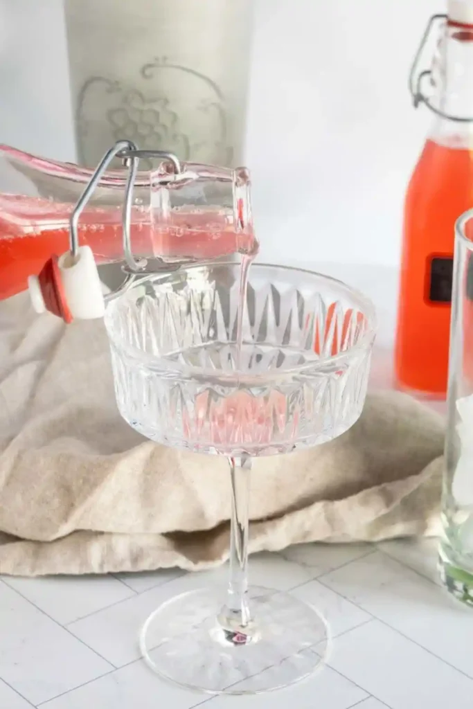 Rhabarbersirup selber machen – Rhabarber Sirup wird in ein Glas eingeschenkt für Getränke und Cocktails