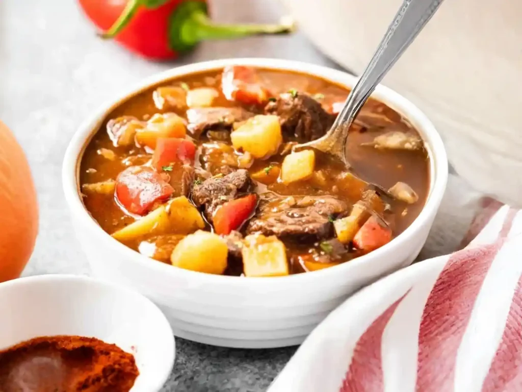 Ungarisches Gulasch Rezept original mit Paprika und Kartoffeln – klassisches ungarisches Rindergulasch mit Löffel serviert