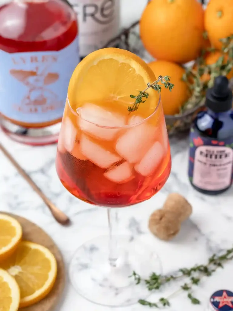 Aperol Spritz alkoholfrei im Glas mit Orangenscheibe, Eiswürfeln, alkoholfreiem Aperol und Sprudel