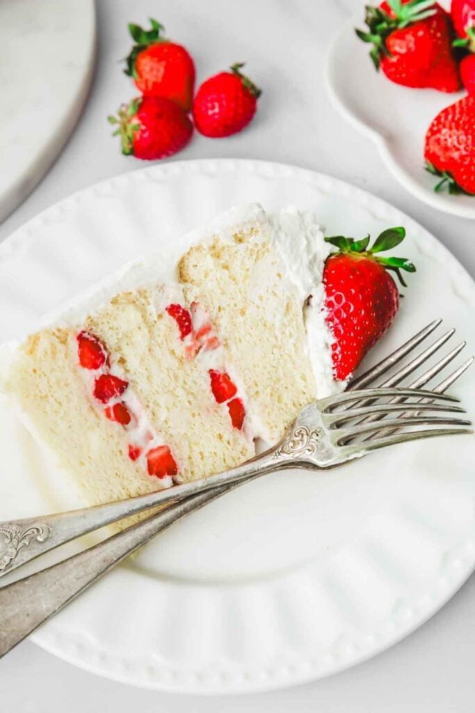 Stück Erdbeertorte mit Sahne und frischen Erdbeeren als einfache Erdbeer-Sahne-Torte auf dem Teller