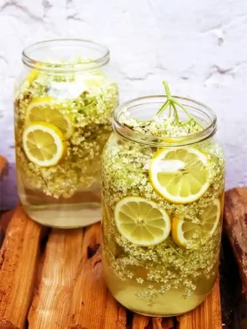 Omas Holunderblütensirup Rezept mit Holunderblüten und Zitronen in Gläsern zum selber machen