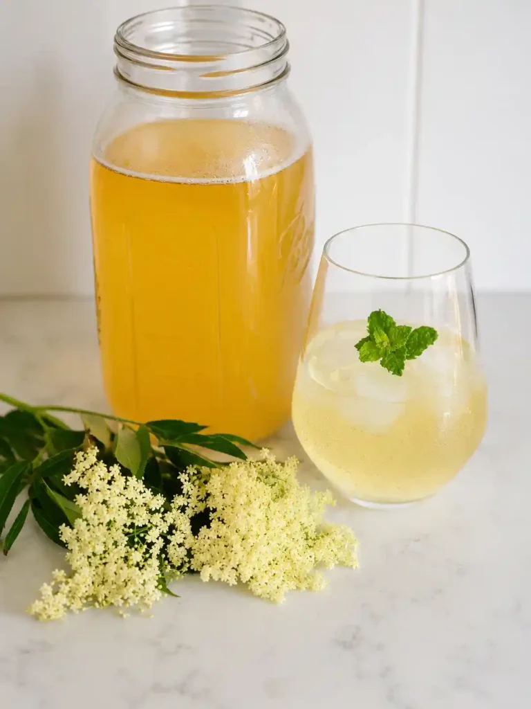 Omas Holunderblütensirup Rezept mit fertigem Holunderblütensirup, frischen Holunderblüten und Getränk im Glas