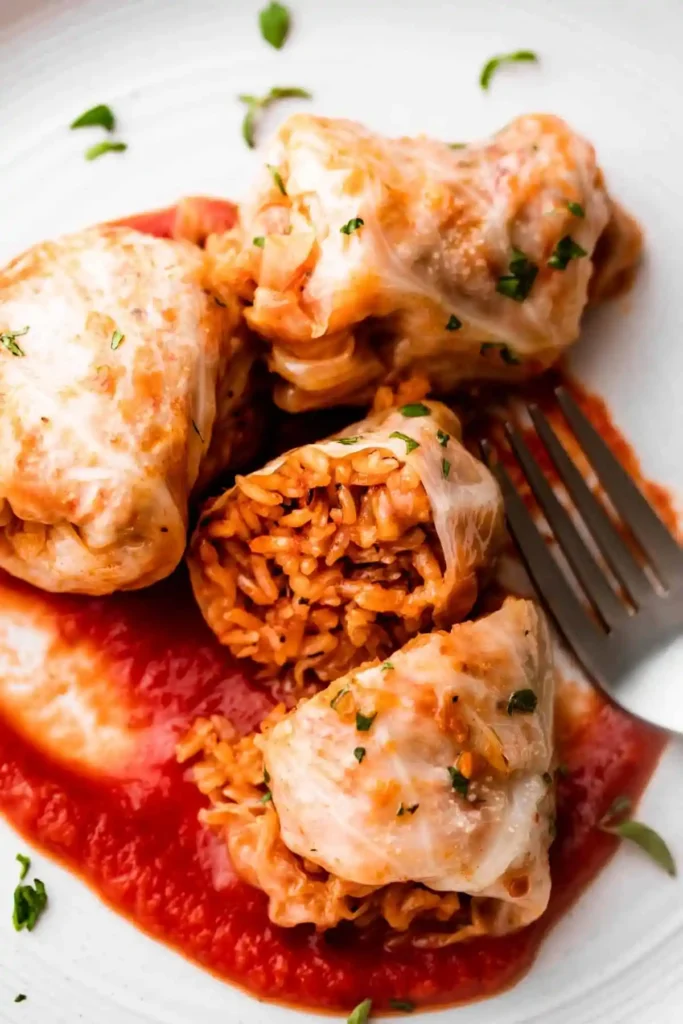 Sarma Rezept original mit Reis und Hackfleisch serviert auf Tomatensauce als serbische Sarma