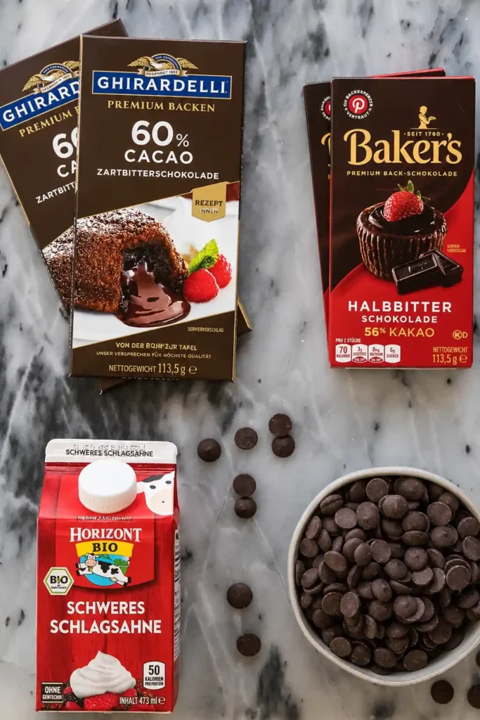 Zutaten für Schokolade Ganache Rezept mit Zartbitterschokolade, Schokotropfen und Sahne auf Marmorfläche