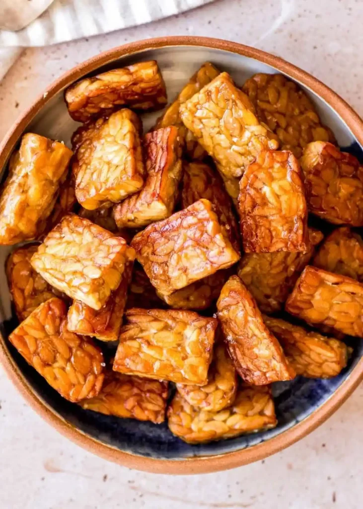 Tempeh zubereiten und braten mit knusprig goldbraunen Tempeh-Stücken in einer Schüssel