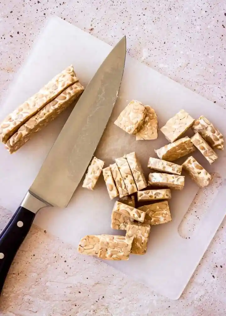 Tempeh zubereiten und braten mit geschnittenem Tempeh auf Schneidebrett als einfaches Tempeh Rezept
