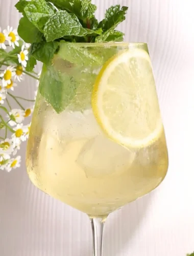 Hugo alkoholfrei im Weinglas mit Minze, Zitrone, Eiswürfeln und Holunderblütensirup