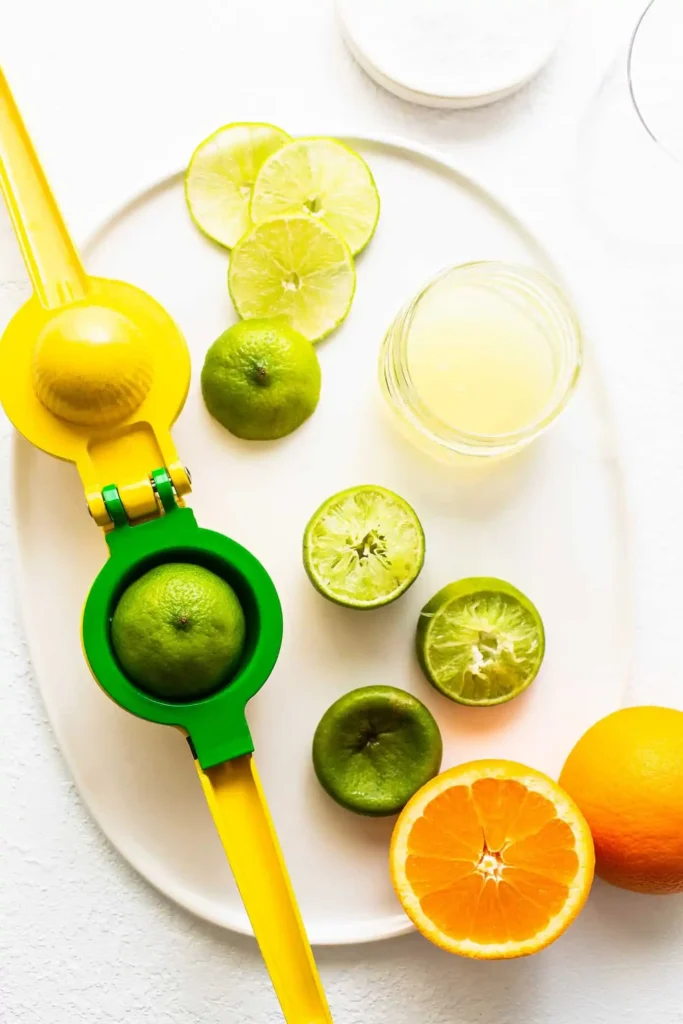 Frische Limetten und Orangen mit Zitruspresse für eine Margarita ohne Alkohol