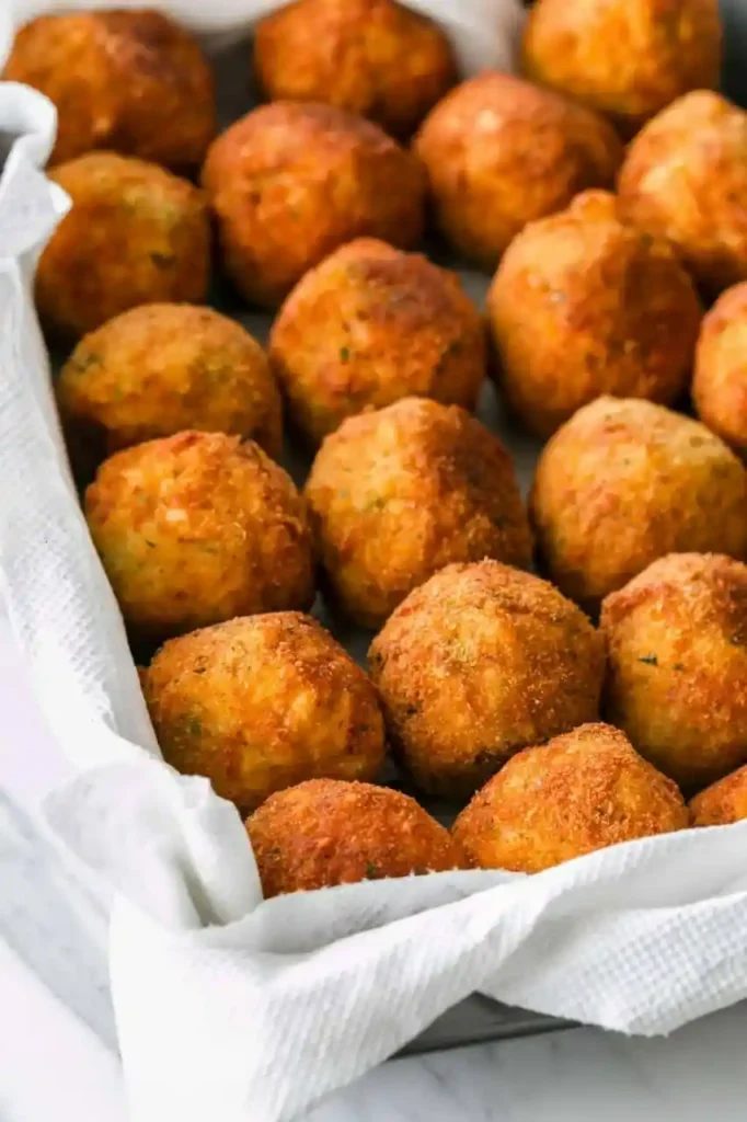 Goldbraun frittierte Arancini di Riso auf Küchenpapier – knusprige gefüllte sizilianische Reisbällchen