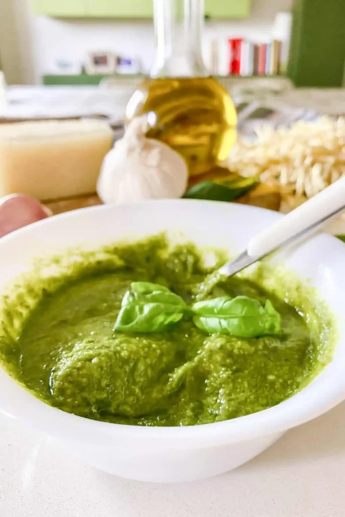 Cremiges grünes Basilikum-Pesto Genovese in einer weißen Schale mit frischem Basilikum, Knoblauch, Parmesan, Olivenöl und Trofie.