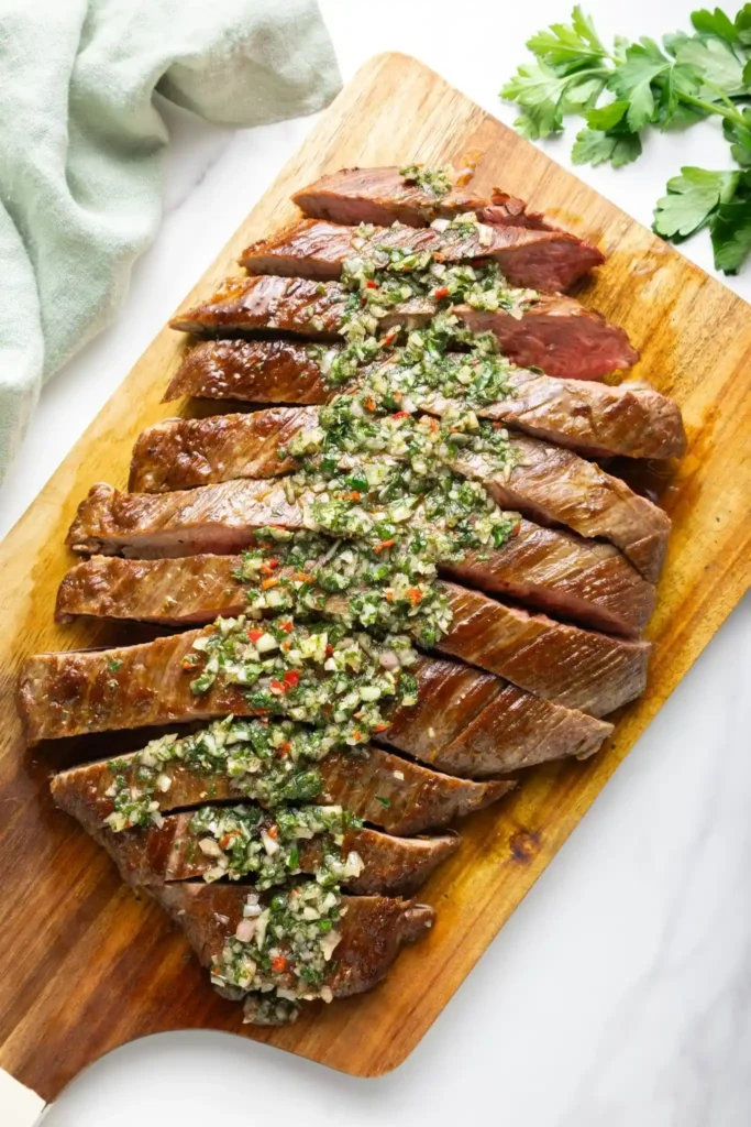 Gegrilltes Steak mit Chimichurri-Sauce nach original argentinischem Rezept auf einem Holzbrett