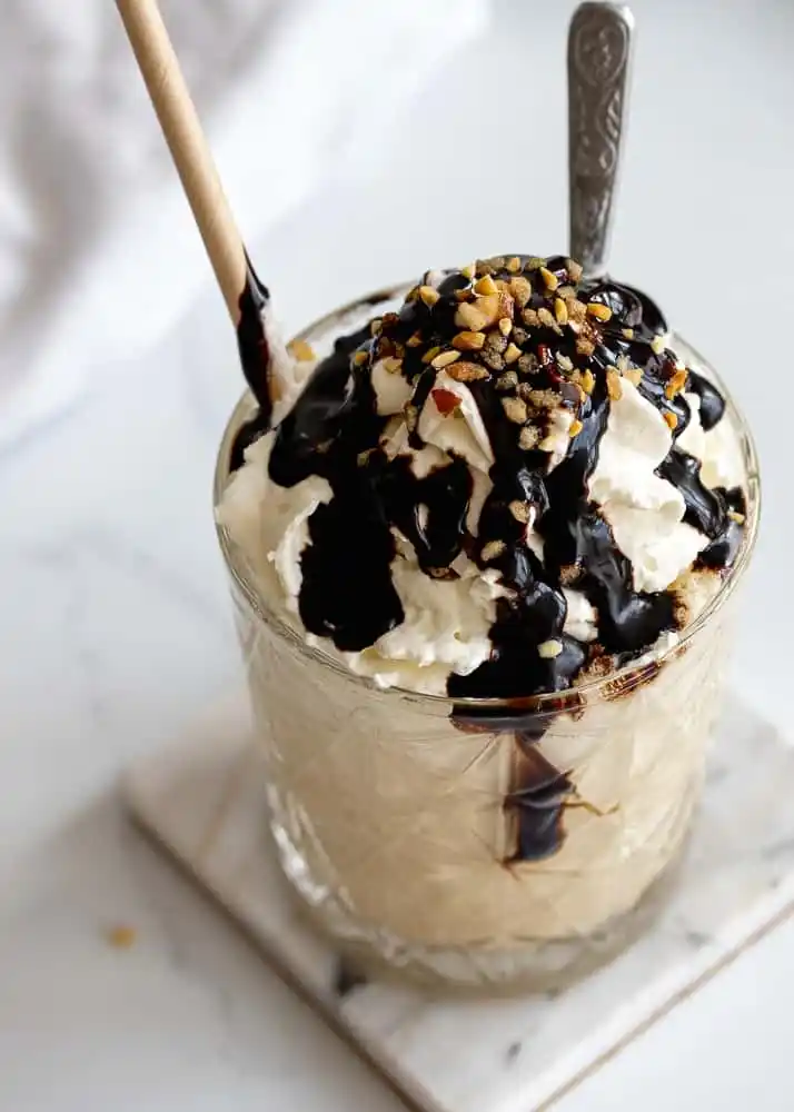 Eiskaffee mit Vanilleeis, Schlagsahne, Schokoladensoße und gehackten Nüssen aus der Vogelperspektive