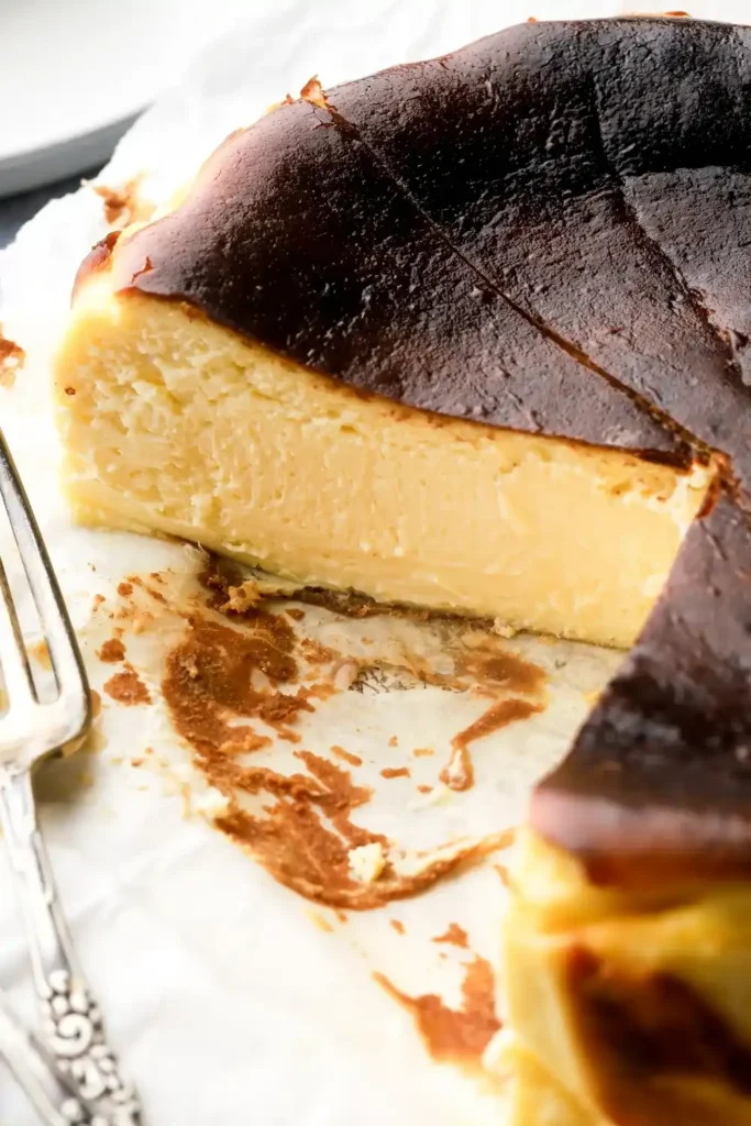 Nahaufnahme eines angeschnittenen San Sebastian Cheesecakes mit dunkler Kruste und cremiger Mitte