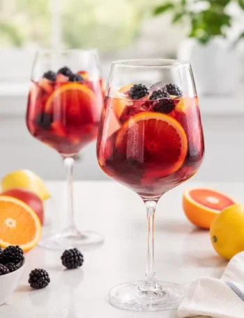 Sangria ohne Alkohol in Weingläsern mit Orangenscheiben, Apfelstücken und Brombeeren