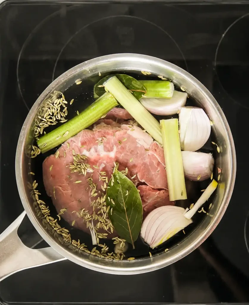 Kalbfleisch für Vitello Tonnato wird mit Sellerie, Zwiebel, Lorbeer und Fenchelsamen im Topf gegart