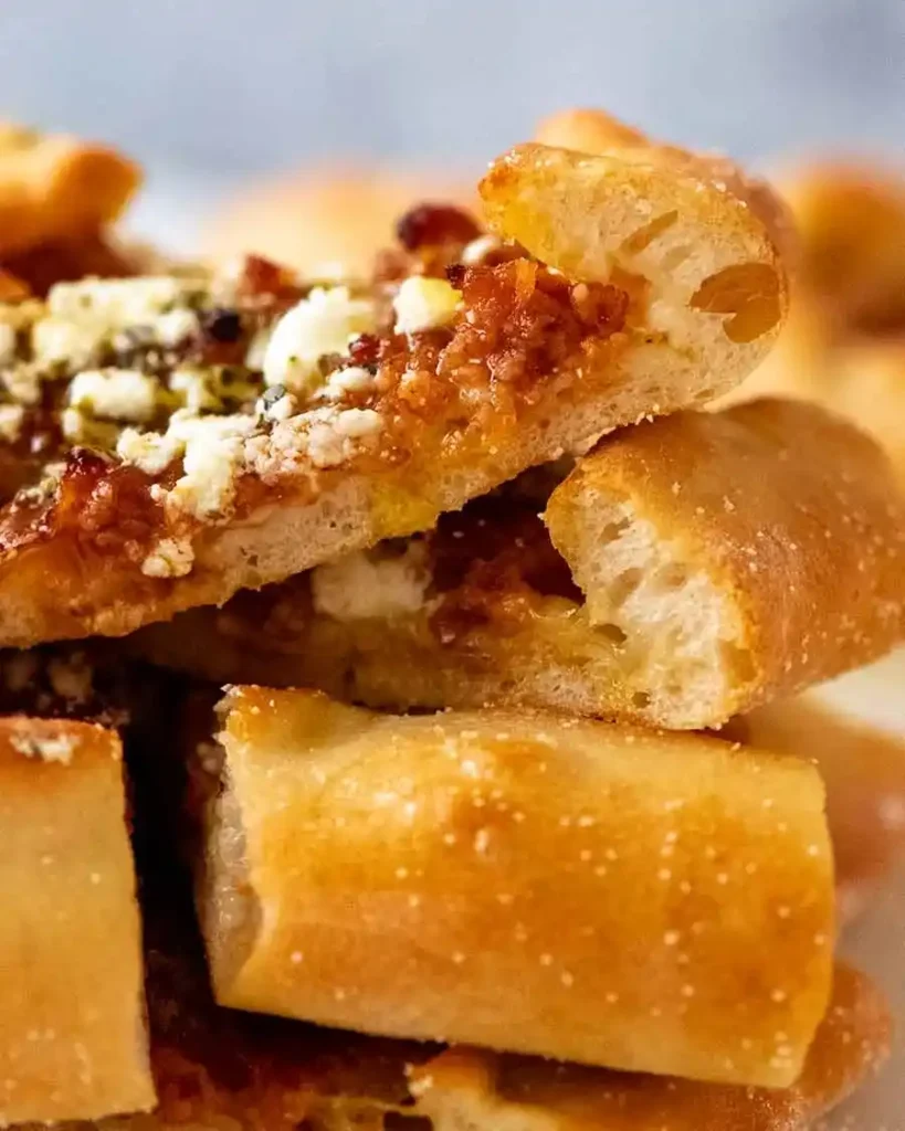 Nahaufnahme einer türkischen Pide mit Hackfleisch, Feta und frischen Kräutern.