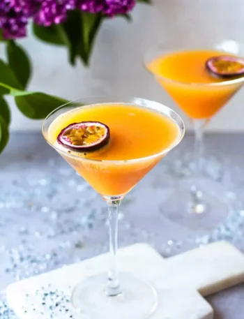 Zwei alkoholfreie Pornstar Martini Mocktails mit Maracuja in eleganten Cocktailgläsern auf einem festlich dekorierten Tisch.