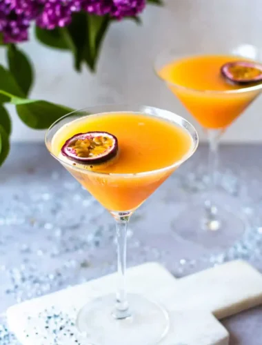 Zwei alkoholfreie Pornstar Martini Mocktails mit Maracuja in eleganten Cocktailgläsern auf einem festlich dekorierten Tisch.