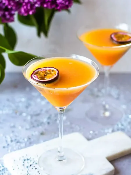 Zwei alkoholfreie Pornstar Martini Mocktails mit Maracuja in eleganten Cocktailgläsern auf einem festlich dekorierten Tisch.