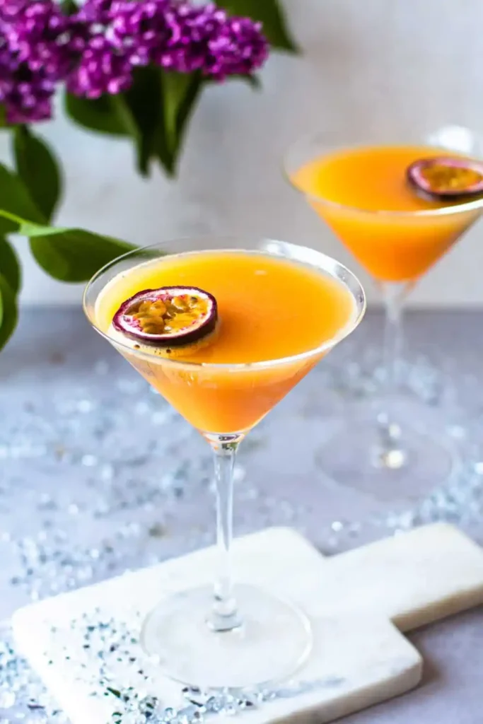 Zwei alkoholfreie Pornstar Martini Mocktails mit Maracuja in eleganten Cocktailgläsern auf einem festlich dekorierten Tisch.